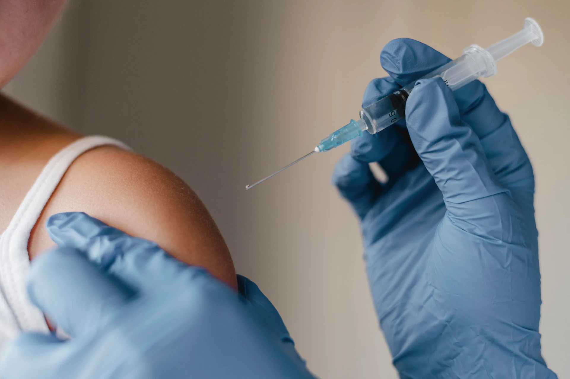 Doctor wearing blue gloves administering a vaccine to a child