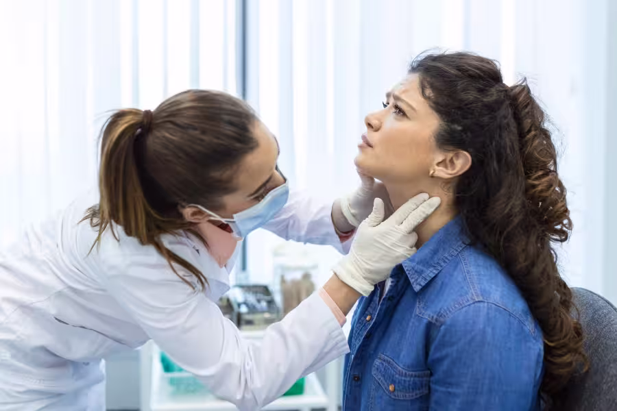 Doctor examining throat of a young woman in the clinic