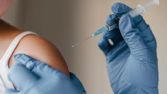 Doctor wearing blue gloves administering a vaccine to a child