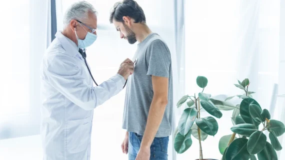 Doctor using a stethoscope to examine a young man